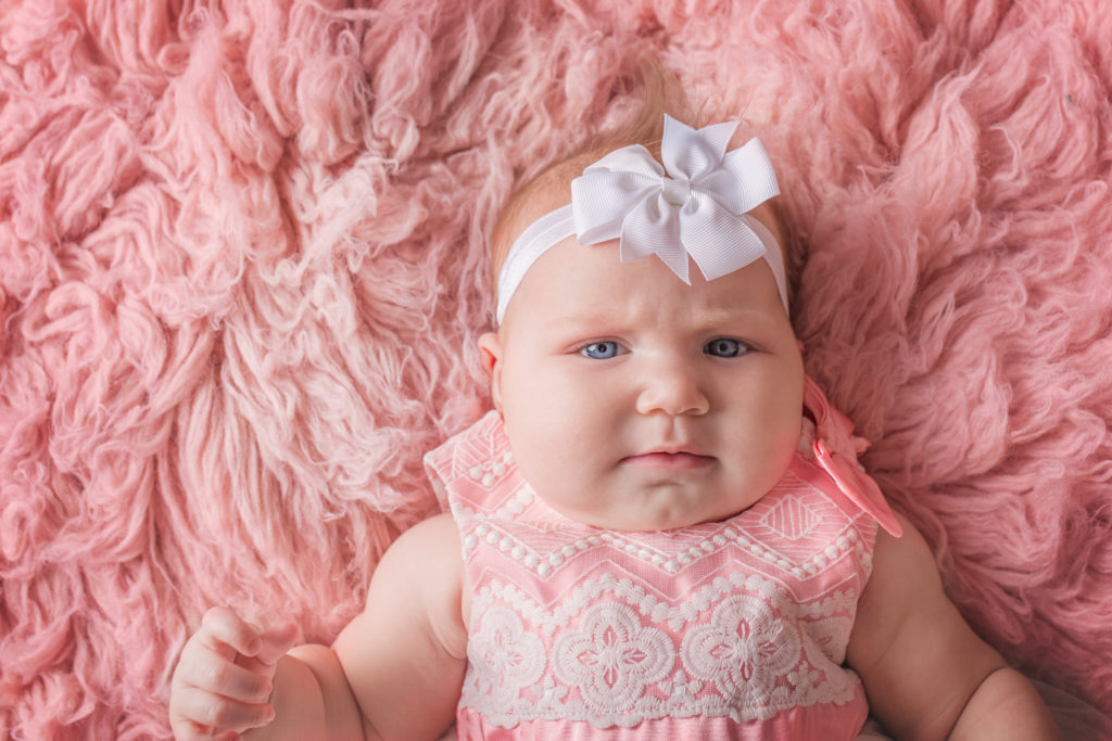 Baby girl in pink dress in photo studio